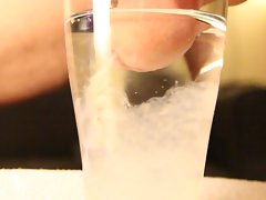 Close-up cumshot of circumcised dick in glass of water